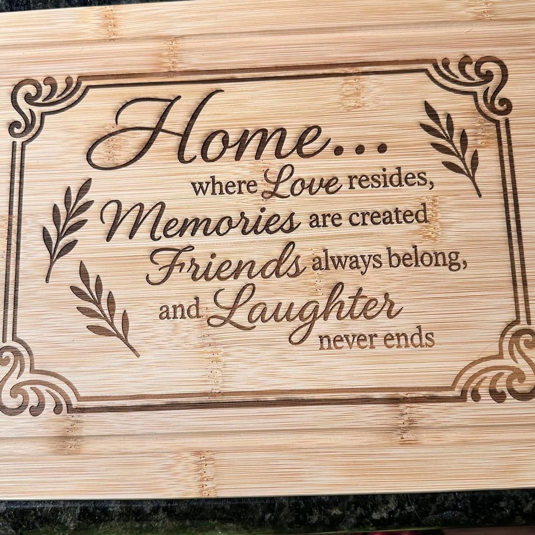 Bamboo cutting board engraved with a decorative frame and a family saying
