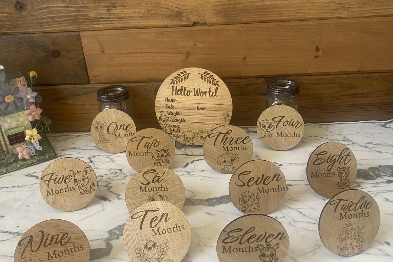 Wooden Hello World birth announcement disc with twelve monthly milestone discs featuring baby animals
